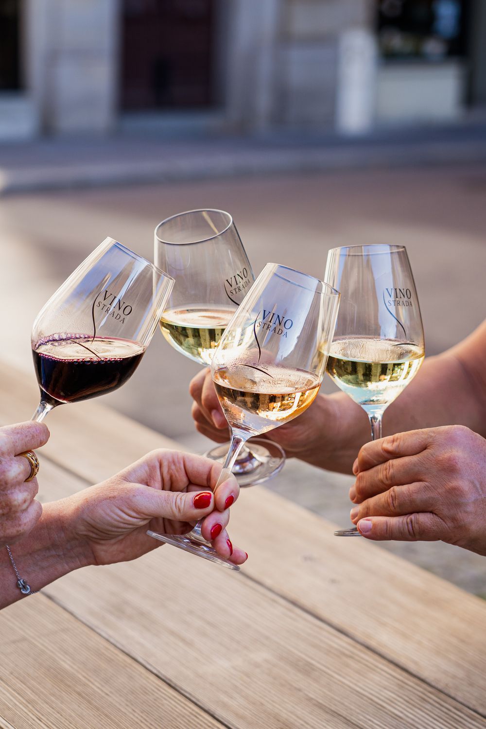 Verres de vin rouge et blanc levés pour trinquer au-dessus d’une table en bois